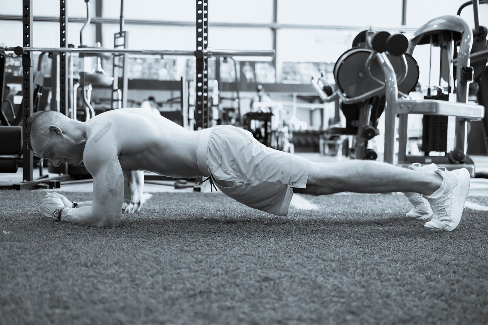 Man performing a plank exercise in a gym setting.