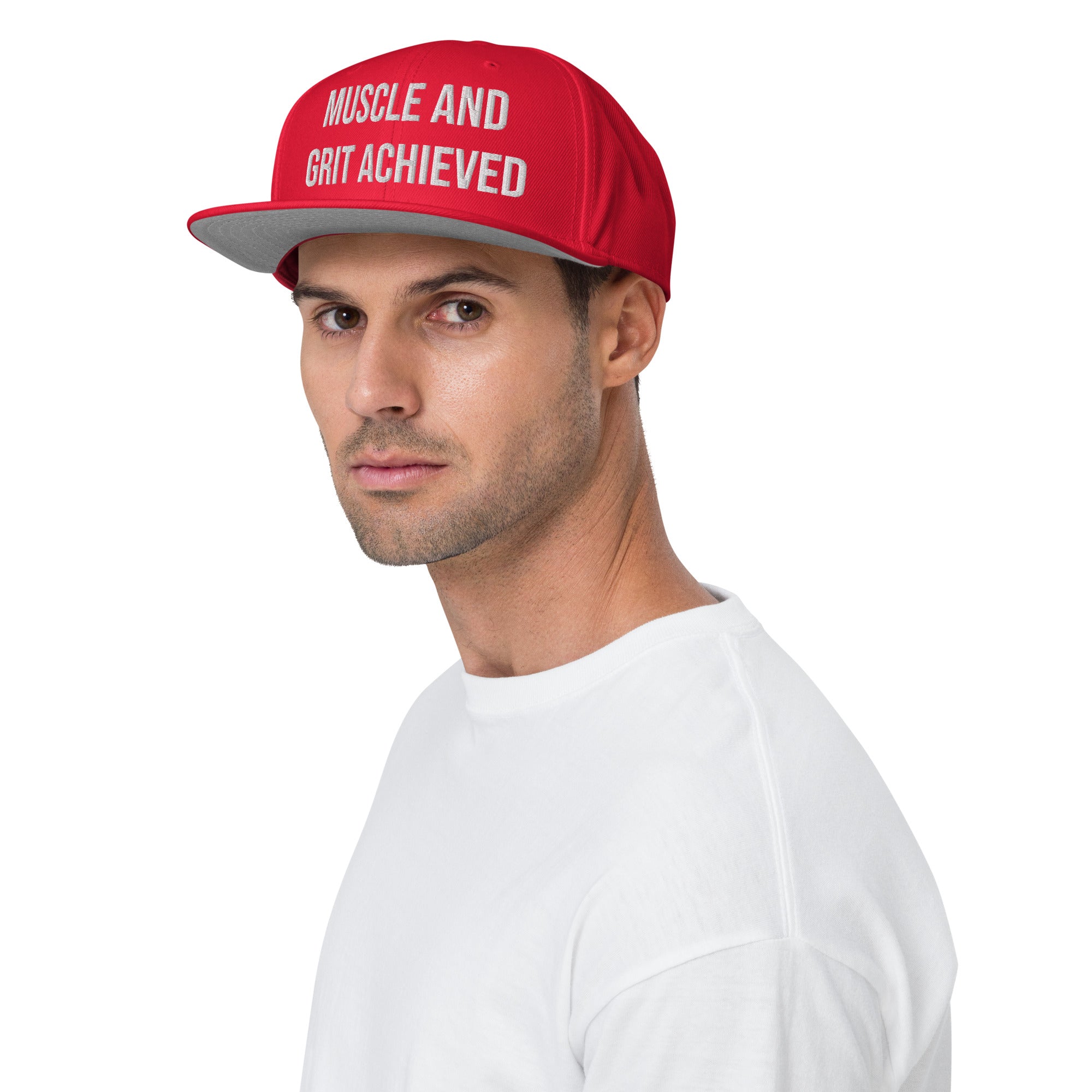 A man wearing a red snapback hat with the embroidered text "Muscle and Grit Achieved," ideal for fitness enthusiasts showcasing their determination and style.