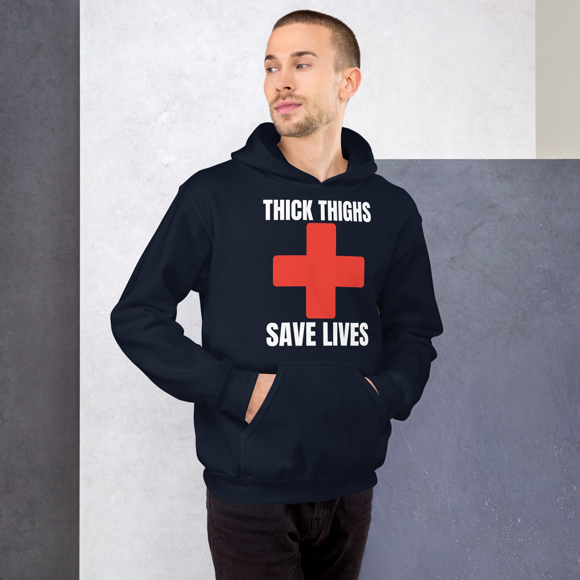 A man wearing a navy hoodie with the "Thick Thighs Save Lives" design featuring a red cross, offering a stylish and cozy option for fitness enthusiasts.